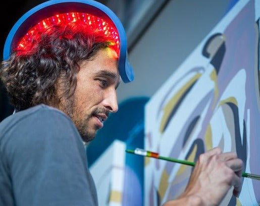 Man wearing a red-light Celluma panel while painting