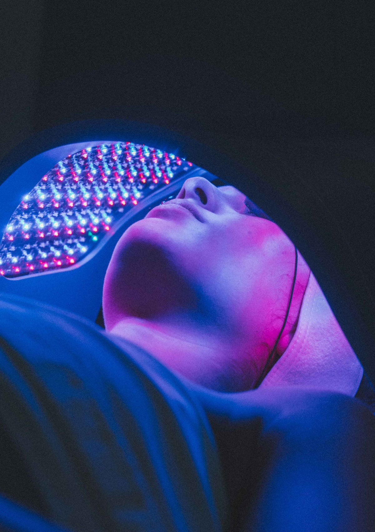 A face beneath a curved blue-light panel in a darkened room