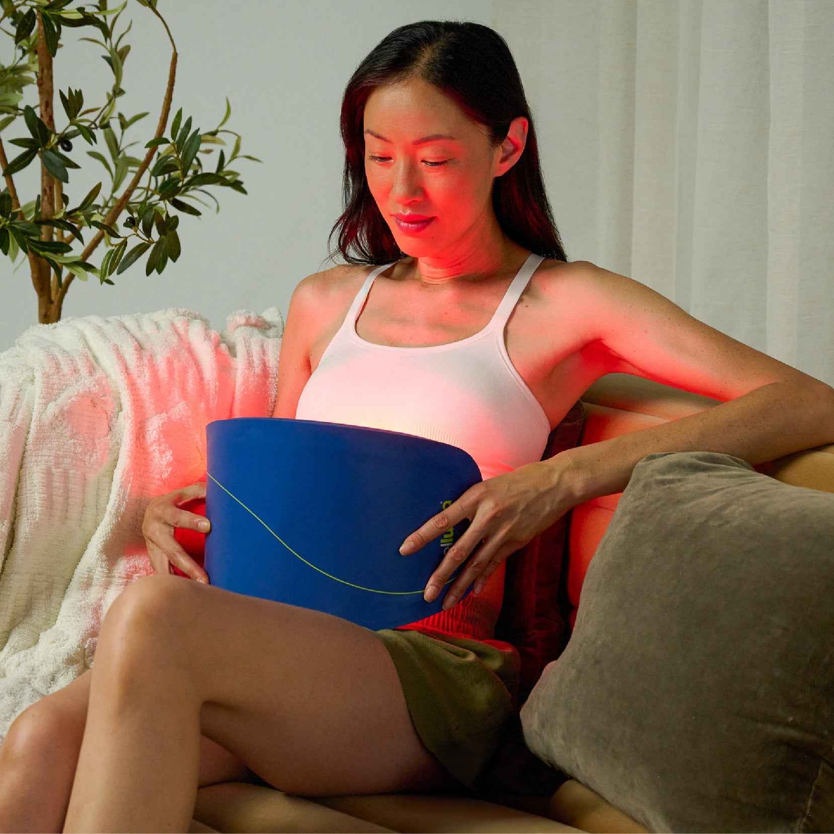 A woman using Celluma NOVA Led Red Light Therapy for body contouring on the belly.