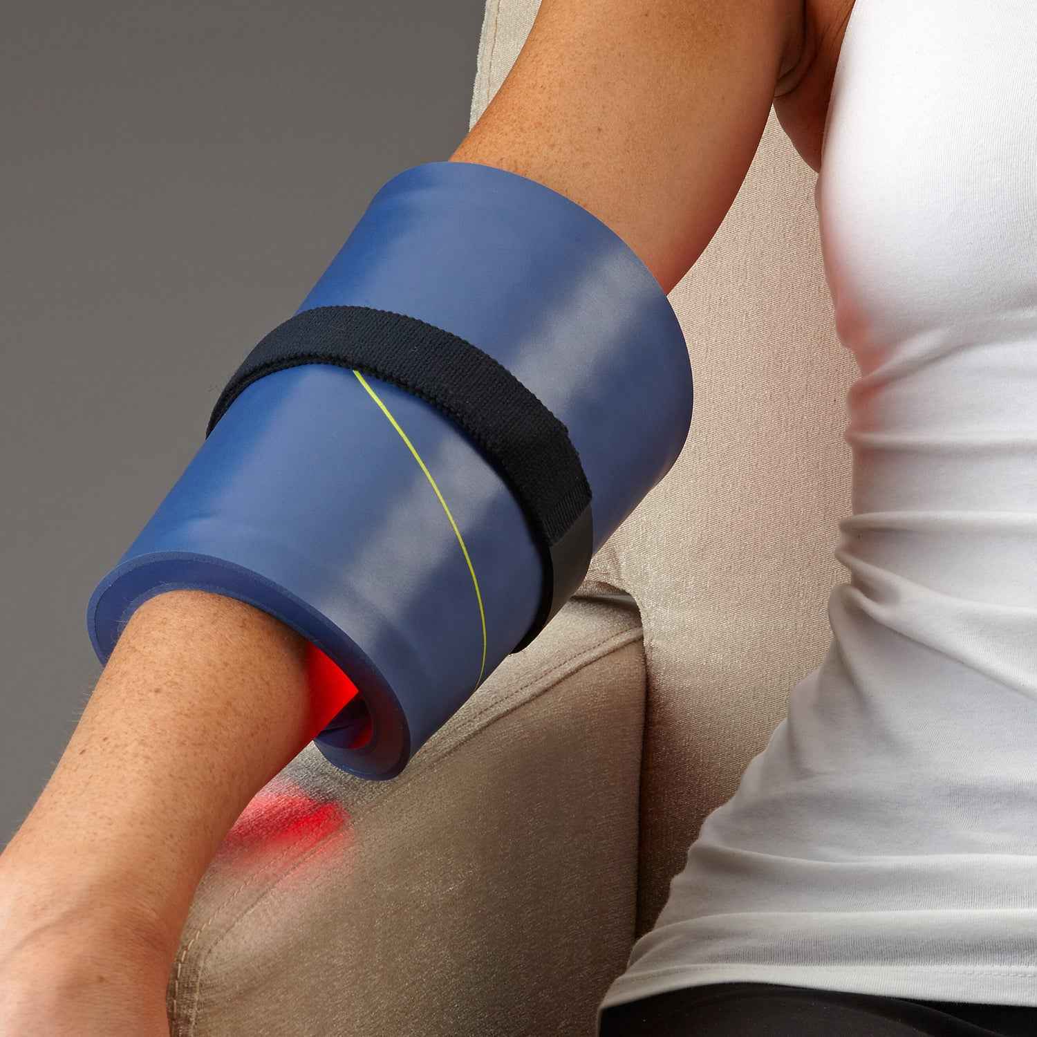 A Woman using Celluma HOME II is Advanced LED Red light Therapy for Pain Relief on her hand with a velcro strap.