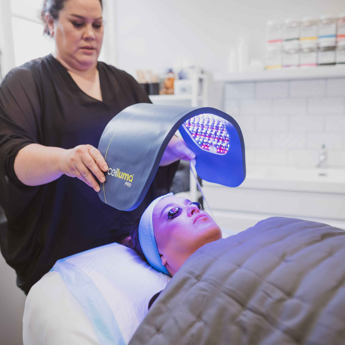 Practitioner positioning a blue panel for a facial session