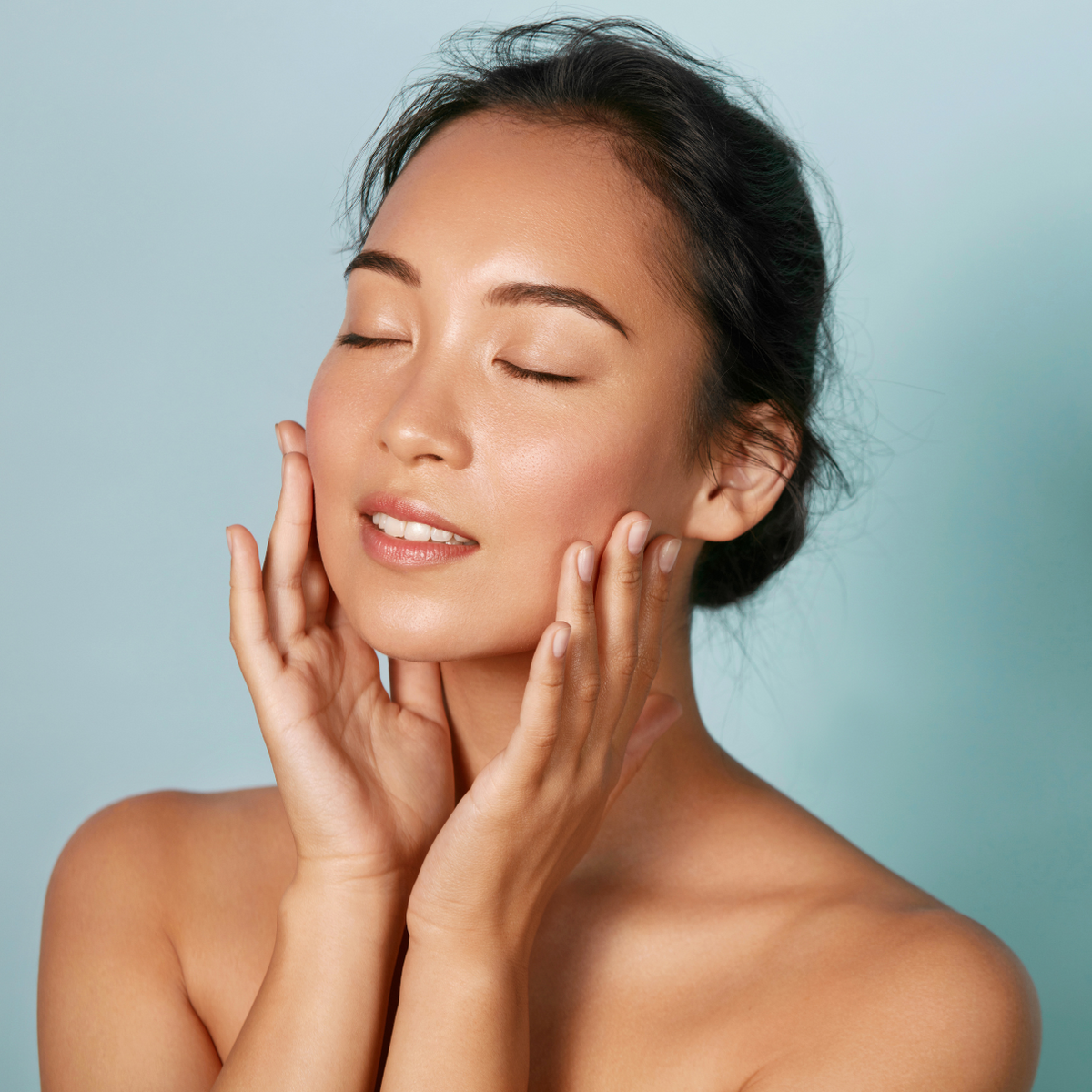 Woman with closed eyes gently touching her cheeks