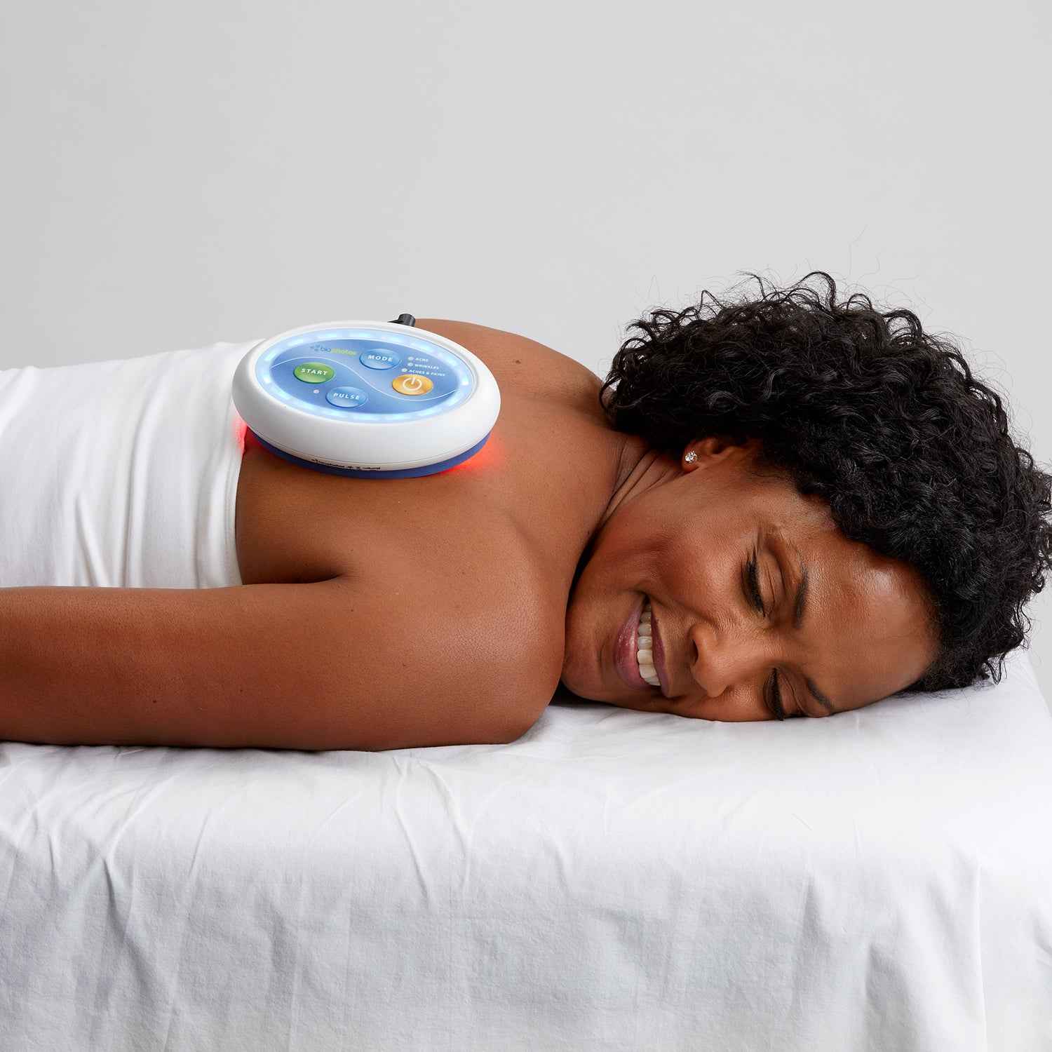 A woman using Celluma POD LED red light therapy to treat pain on her back.