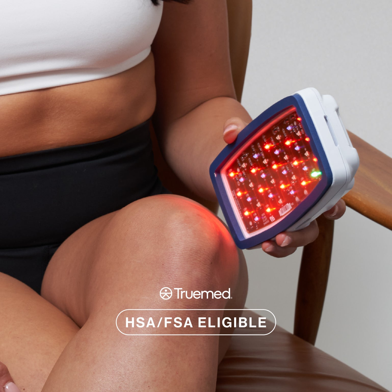 Celluma POD Series 2 handheld LED device being used for knee pain relief with adjustable strap. This HSA/FSA eligible 4-mode medical machine is FDA-cleared for treating arthritis, localized muscle pain, acne, and over-the-counter body contouring.