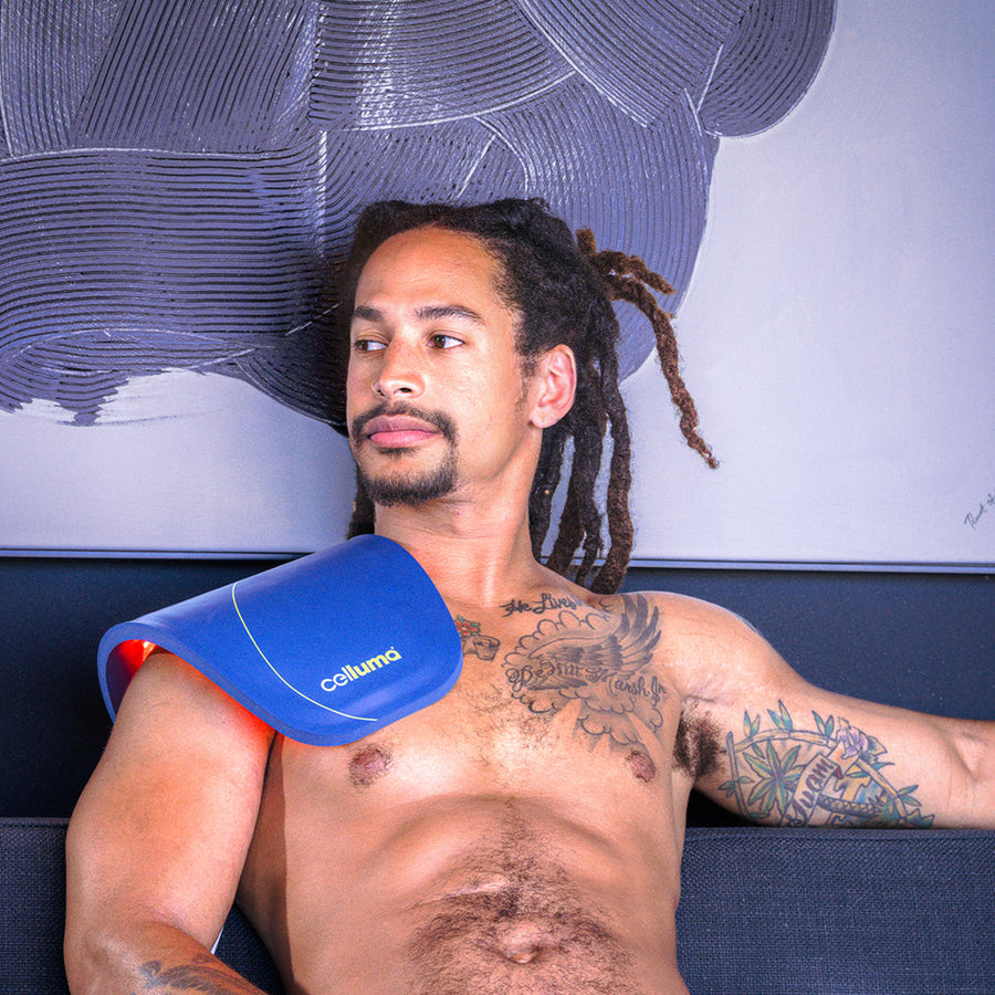 man using celluma red light therapy device on his shoulders treating for pain relief