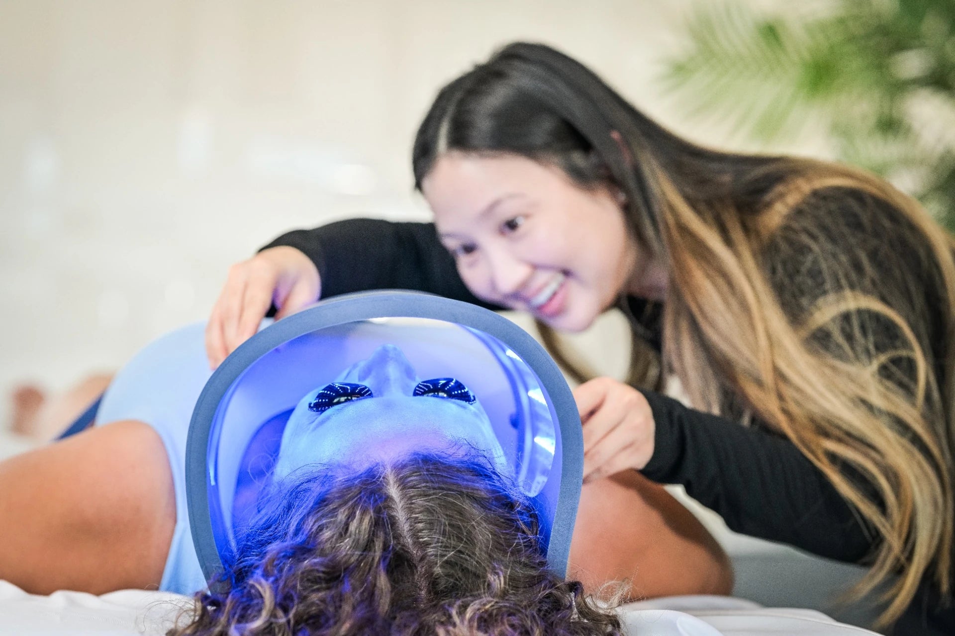 专业人员将亮着蓝光的 Celluma LED 光疗板置于客人面部上方，进行专业痤疮护理。